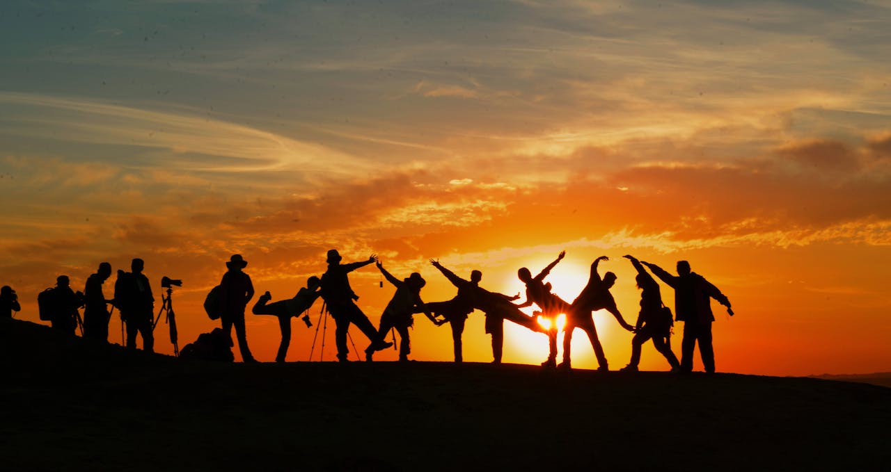 home-hero Group of people silhouetted against a vibrant sunset, showcasing unity and joy.