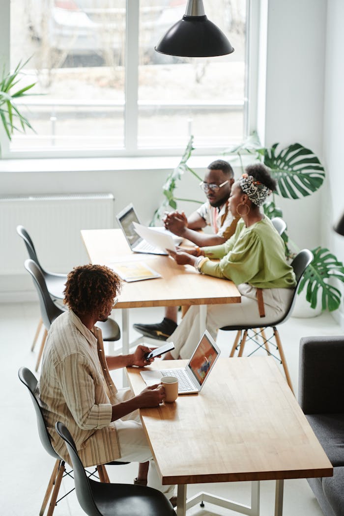 Three colleagues engaged in a brainstorming session at a modern office workspace.